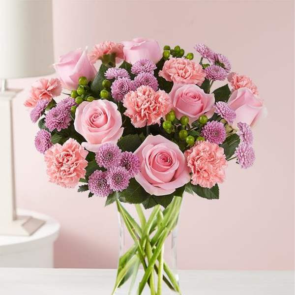 Pink roses, carnations, and purple mums in a clear glass vase