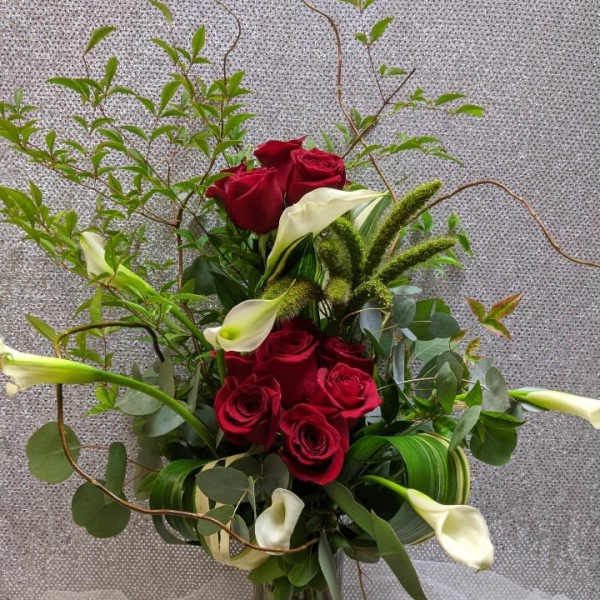 Red roses and white calla lilies in a glass vase