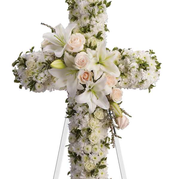 White floral cross on a stand with pale roses and lilies