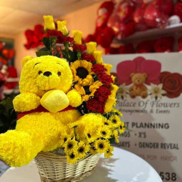 Yellow teddy bear with red and yellow flowers in a wicker basket