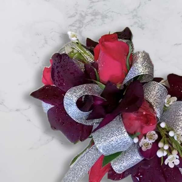 Boutonniere with pink and burgundy roses and silver ribbon
