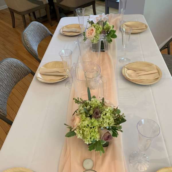 Low floral centerpieces on a set dining table with blush and green blooms