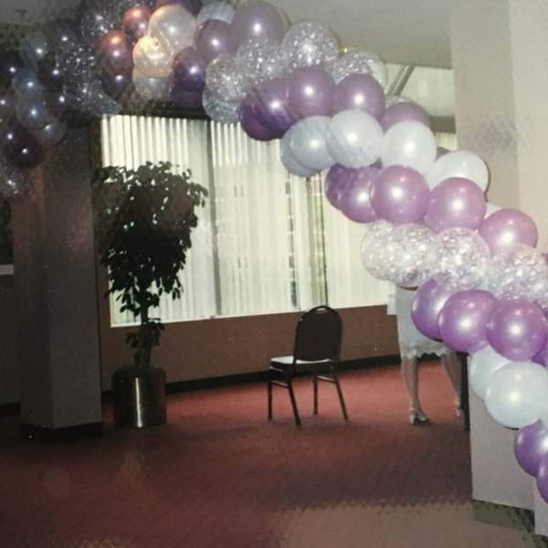 Purple and white balloon arch in an indoor room
