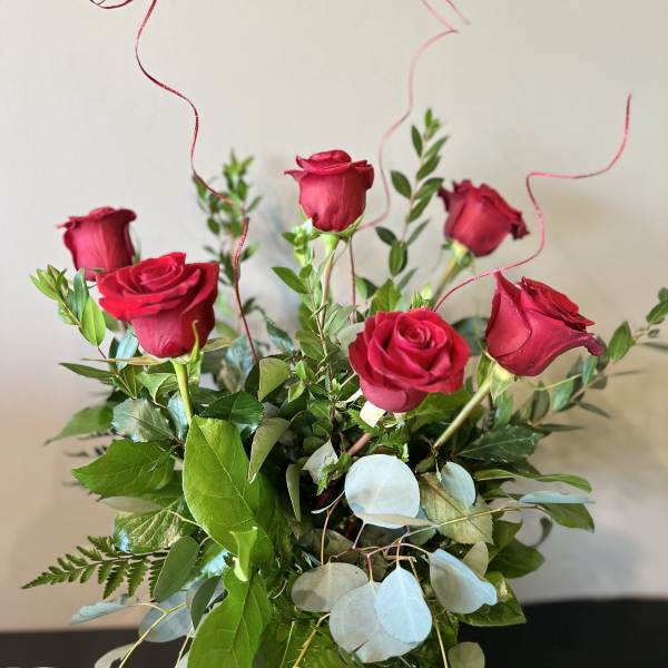 Bouquet of red roses with greenery and curly ribbon accents
