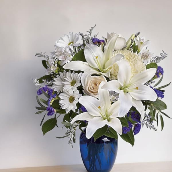 White lilies and daisies arranged in a blue vase