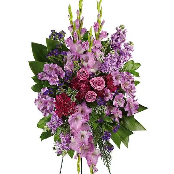 Tall standing spray of purple and pink flowers including roses on a metal easel