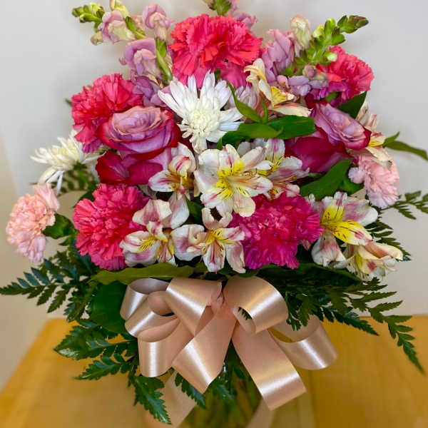 Bouquet of pink carnations, roses, and white alstroemeria with a satin ribbon