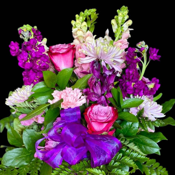 Bouquet of pink and purple flowers with a purple ribbon in a vase