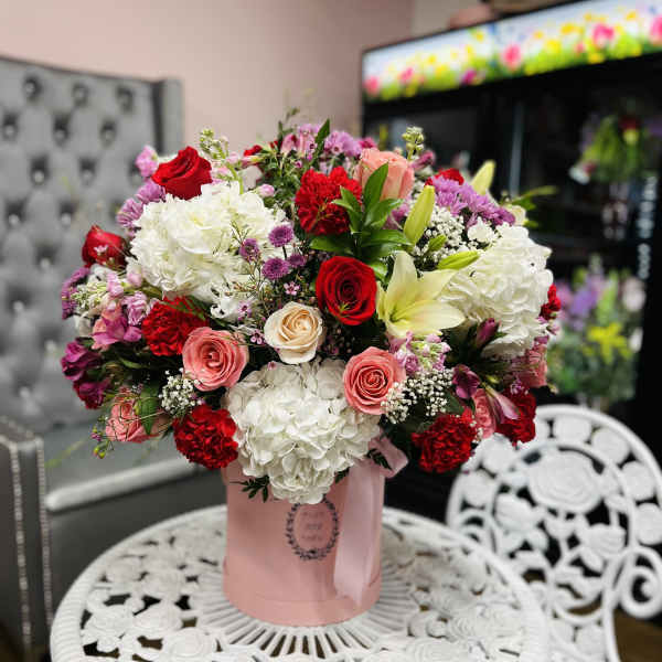 Bouquet of red, pink, and white flowers in a pink hatbox