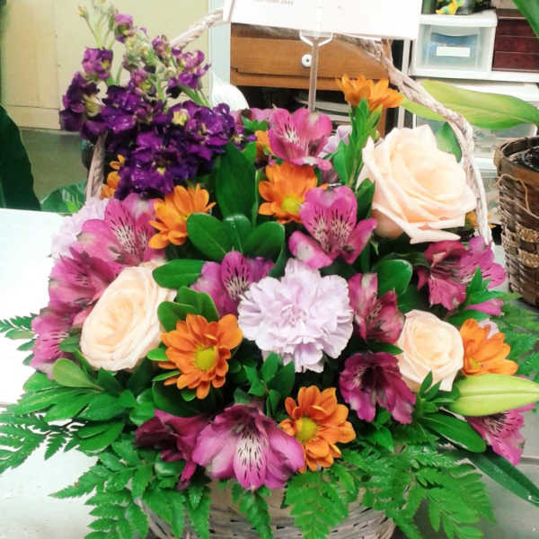 Basket arrangement with pink, orange, and cream flowers