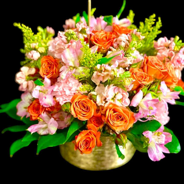 Orange roses and pink flowers arranged in a gold bowl