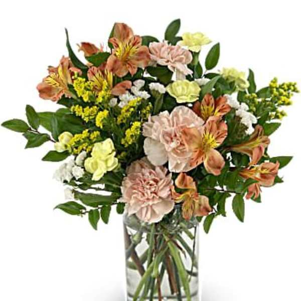 Mixed bouquet of peach and yellow flowers in a clear glass vase