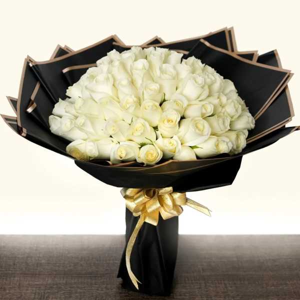 Bouquet of white roses wrapped in black paper with a gold ribbon