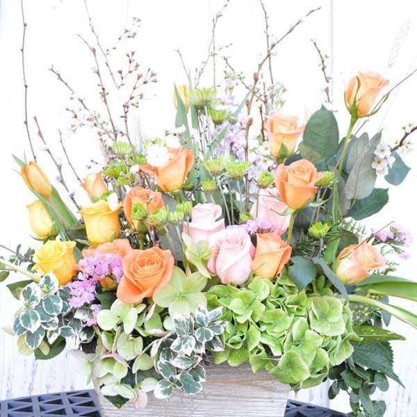 Mixed bouquet of roses, tulips, and hydrangeas in a rectangular container