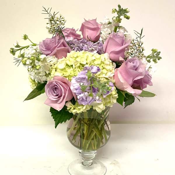 Pink roses and pastel hydrangeas arranged in a clear glass vase