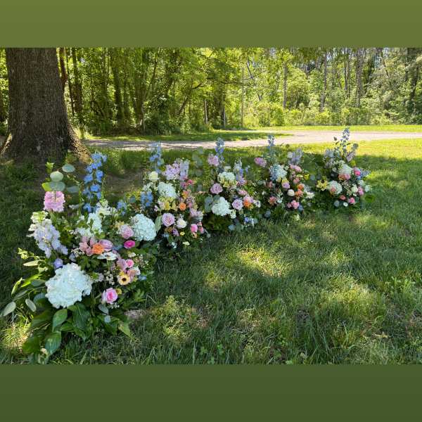 Low floral arrangements in pastel colors placed outdoors on grass