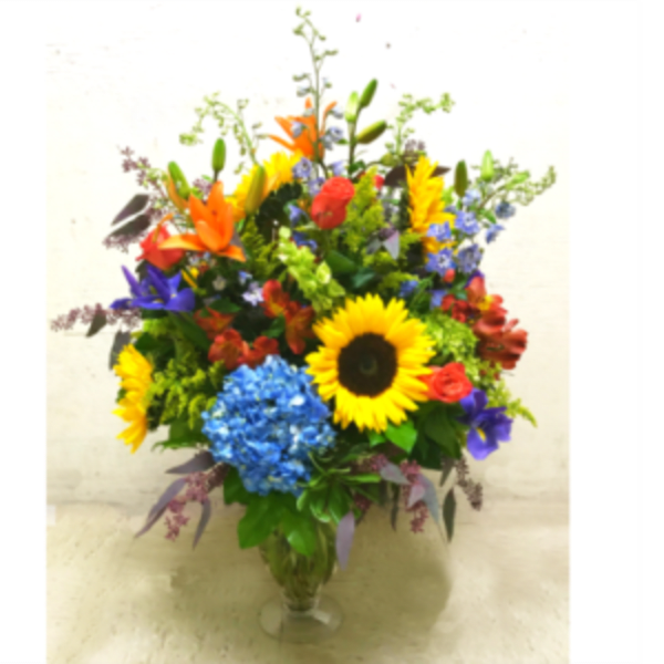 Colorful mixed bouquet in a clear glass vase with sunflowers and lilies