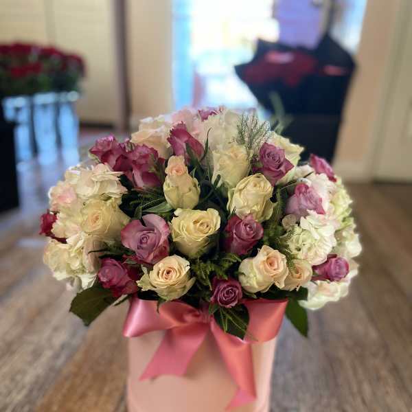 Bouquet of pink and cream roses in a pink hat box with ribbon