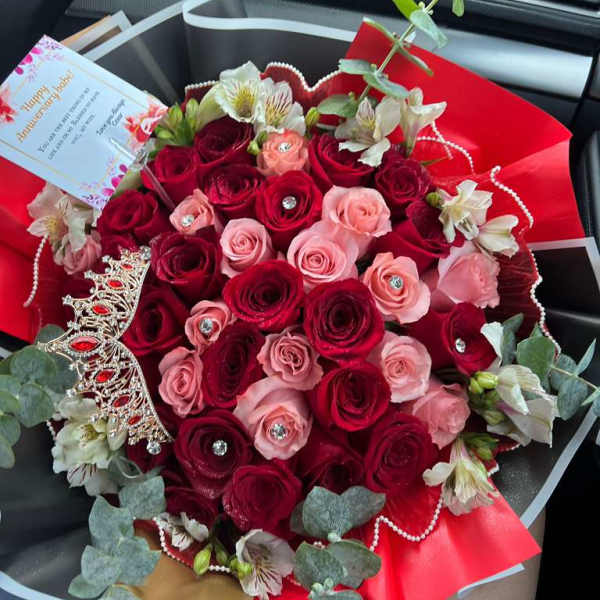 Bouquet of red and pink roses with white alstroemeria and decorative accents