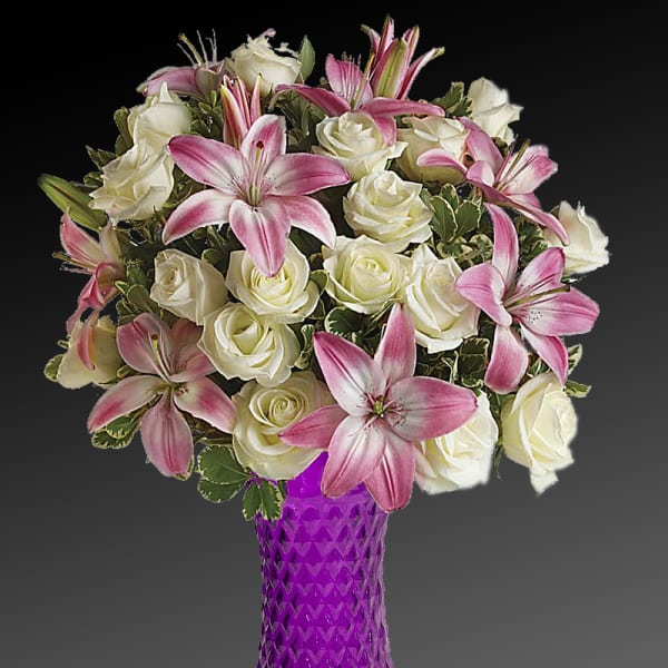 Pink lilies and white roses arranged in a purple vase