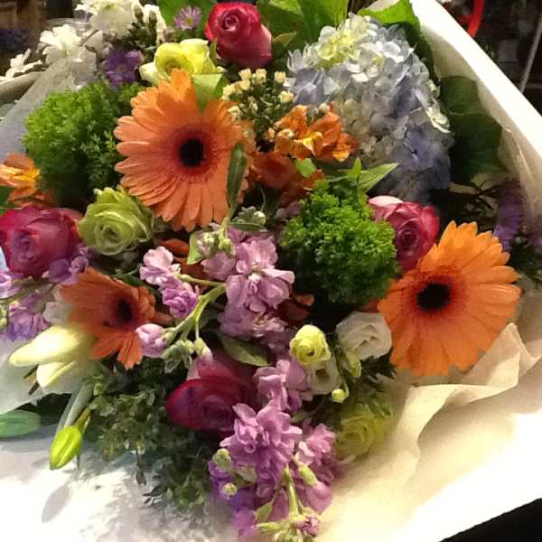 Mixed bouquet with orange gerbera daisies, roses, and purple flowers