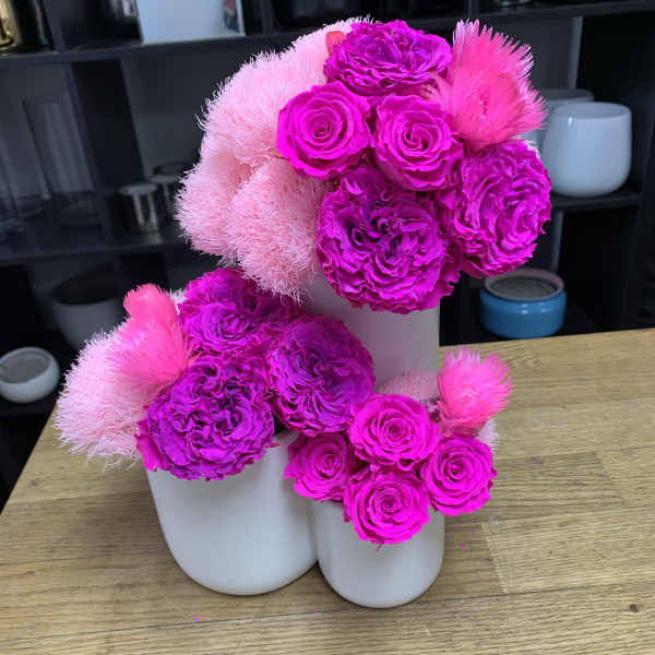 Bright pink floral arrangement in white vases with roses and fluffy blooms