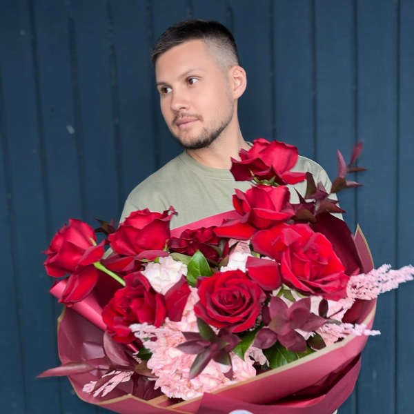 Man holding a large bouquet of red roses and pink flowers
