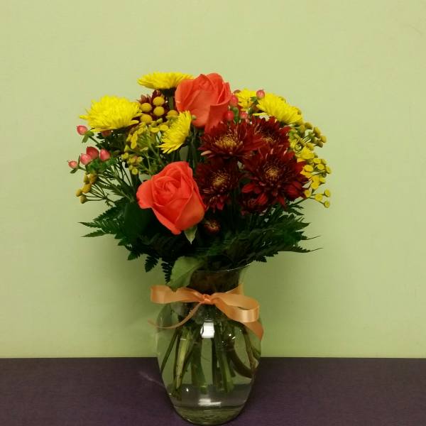 Bouquet of orange roses and yellow chrysanthemums in a glass vase