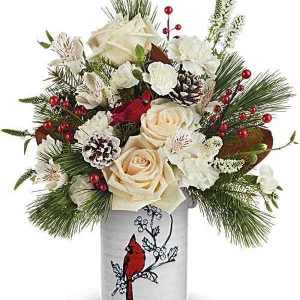 Cream roses and white flowers in a decorative vase with pine and red berries