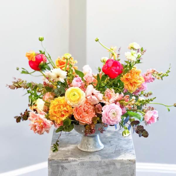 Colorful mixed flower arrangement in a white pedestal vase