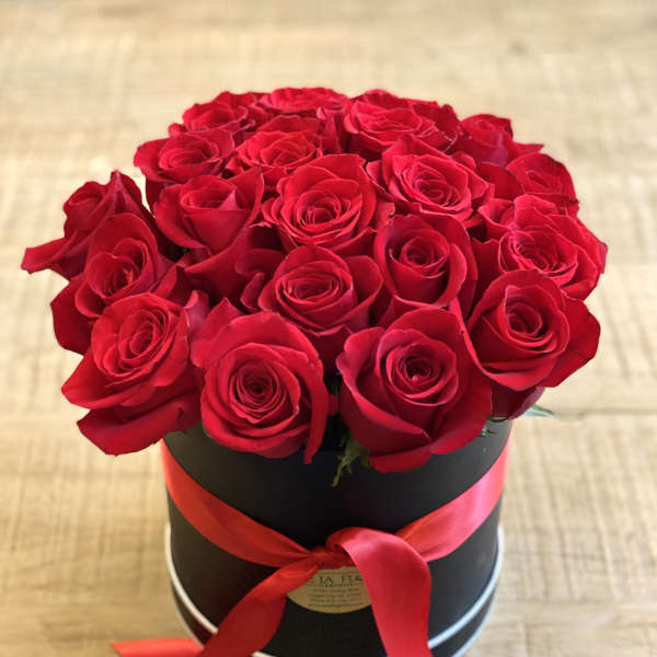 Red roses arranged in a black round box with a red ribbon