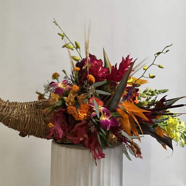 Tropical floral arrangement in a woven horn-shaped container