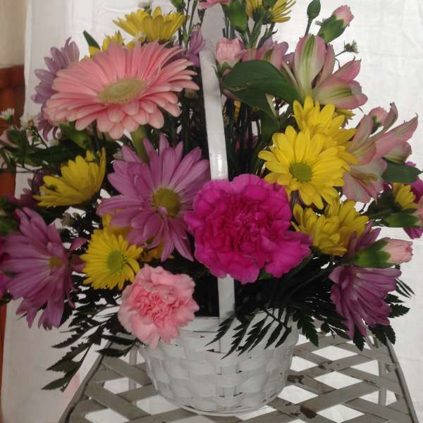 Mixed pink, yellow, and purple flowers in a white basket