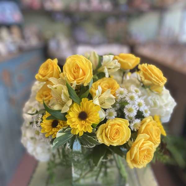 Yellow roses and daisies arranged in a glass vase