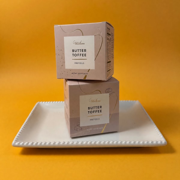 Two butter toffee pretzel boxes stacked on a white tray.