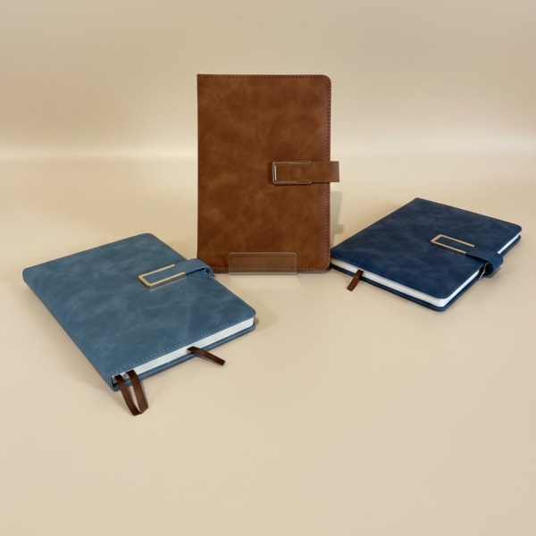 Three leather-bound notebooks in blue and brown with metal clasps
