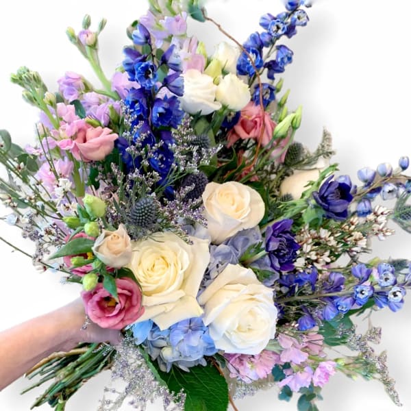 Handheld bouquet of white, pink, and blue flowers with long stems