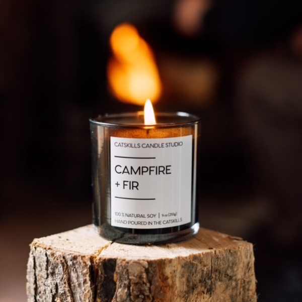 Lit candle in a glass jar on a wood stump