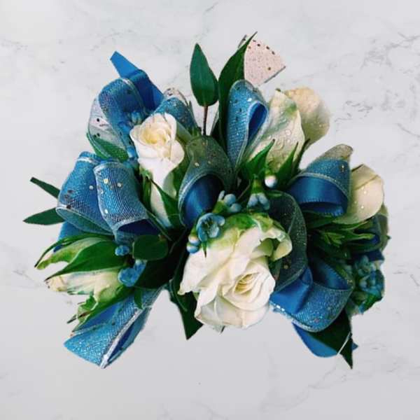 White roses with blue ribbon loops and green leaves in a bouquet
