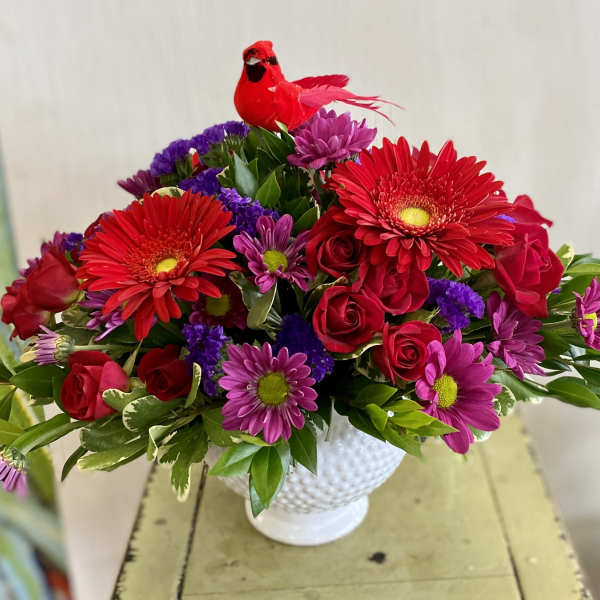 Red and purple mixed bouquet in a white vase with a red bird decoration