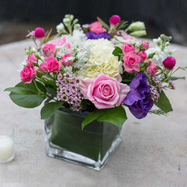 Pink and purple rose bouquet in a square glass vase