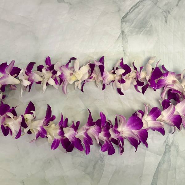 Purple and white orchid lei on a pale fabric background