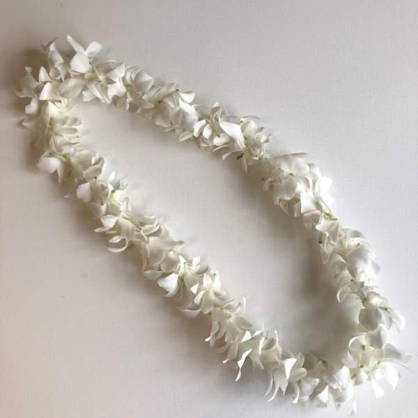 White flower lei on a plain light background