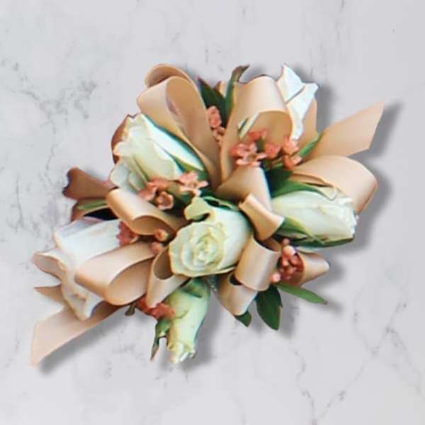 Cream rose bouquet with peach ribbon loops on a light marble surface