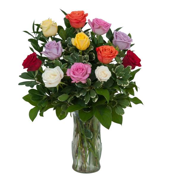 Mixed roses in a clear glass vase with dense greenery