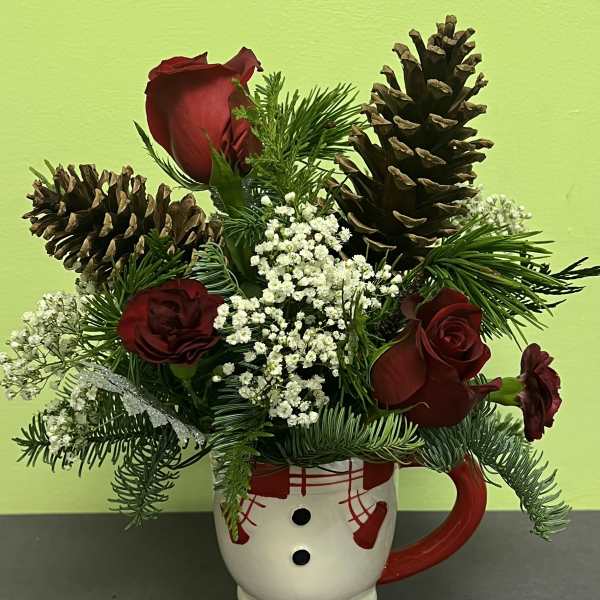 Red roses and pinecones arranged in a snowman mug