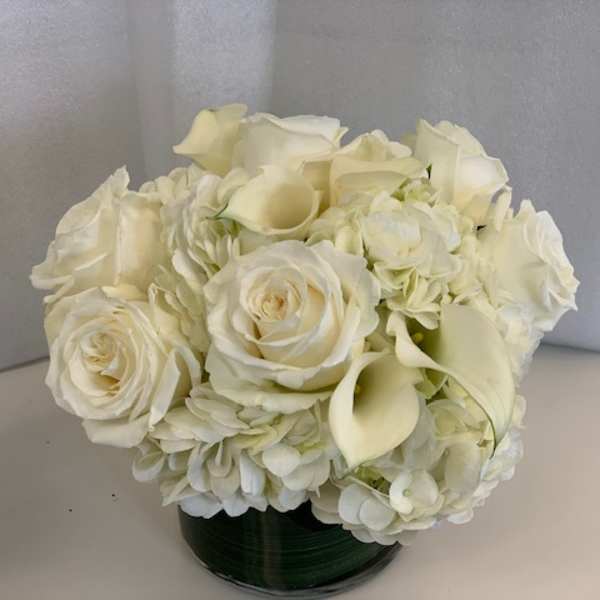 White roses and calla lilies arranged in a low dark vase