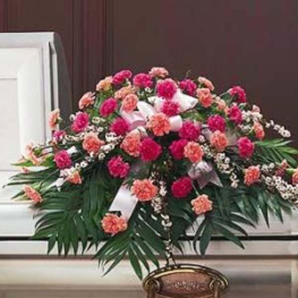 Pink and peach carnation casket spray with white ribbon