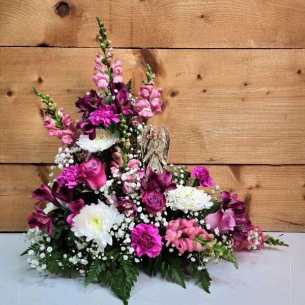 Pink and white floral arrangement with an angel figurine
