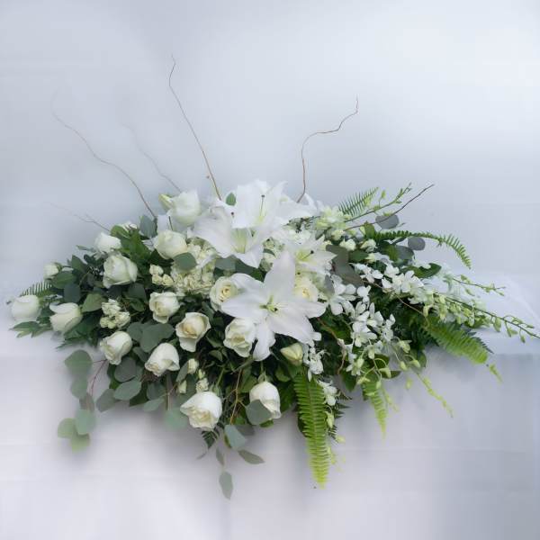 White floral casket spray with lilies and roses